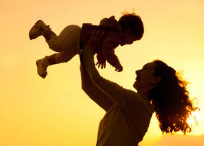 Silhouette of mother which turns the child against a sunset and water